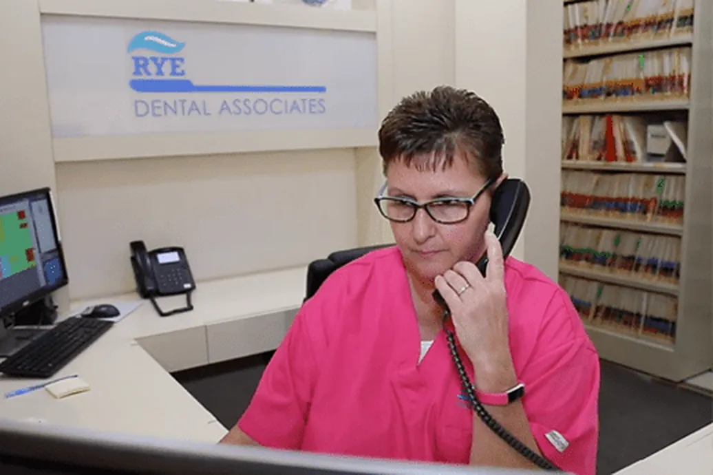Reception at Rye Dental Associates, taking a call under the practice sign.
