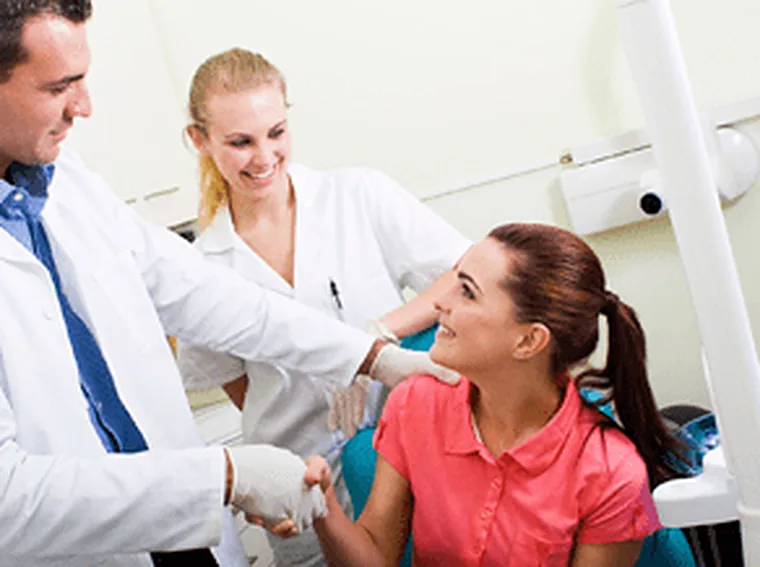 A dentist and assistant treating a patient at a routine appointment.